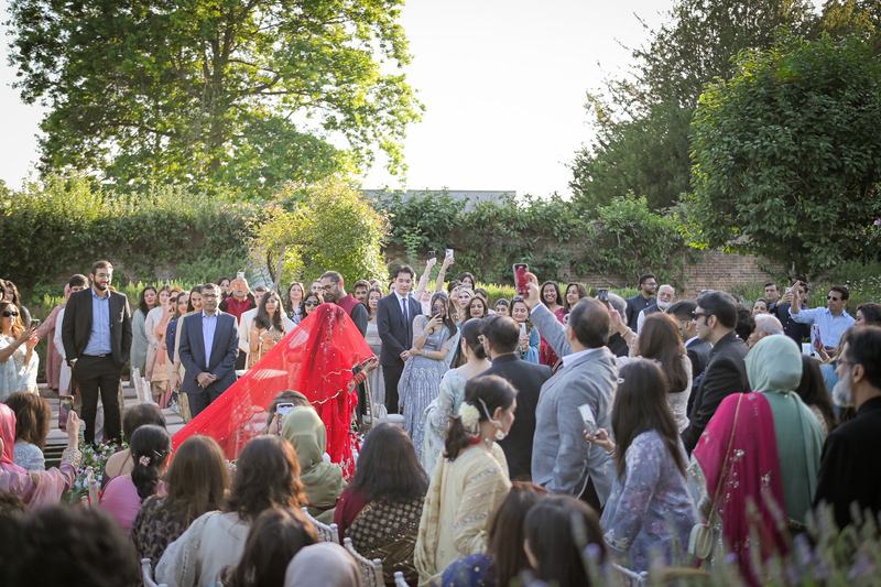 Bride in red veil at outdoor Pakistani wedding ceremony