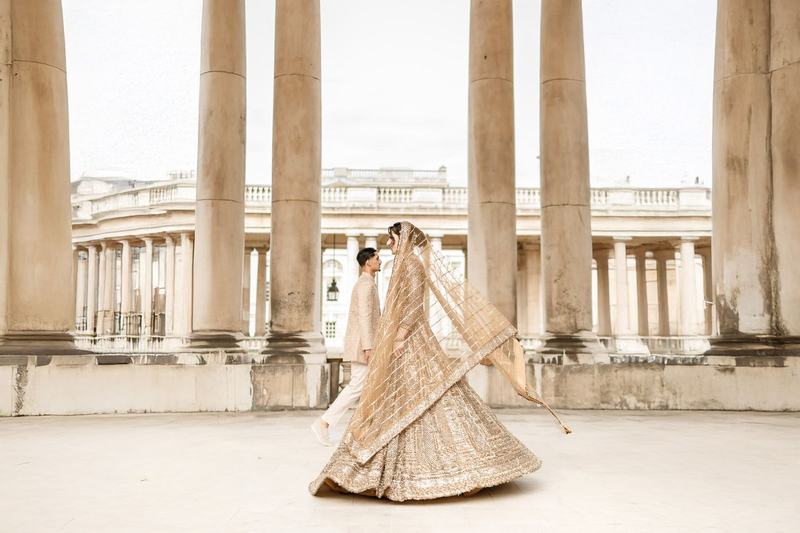 Bride twirling in a golden lehenga at a colonnade