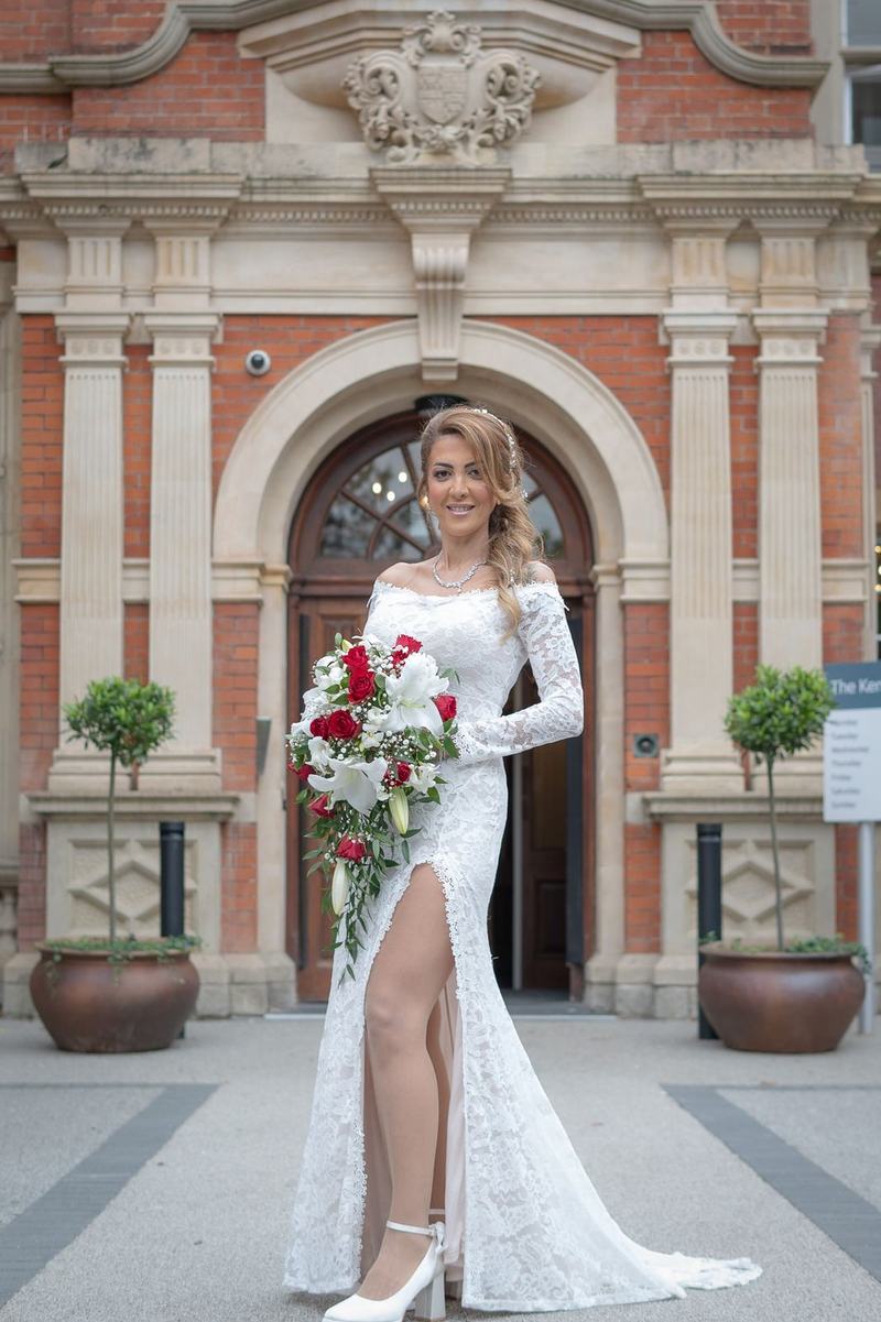 Bride in lace gown holding a red and white bouquet