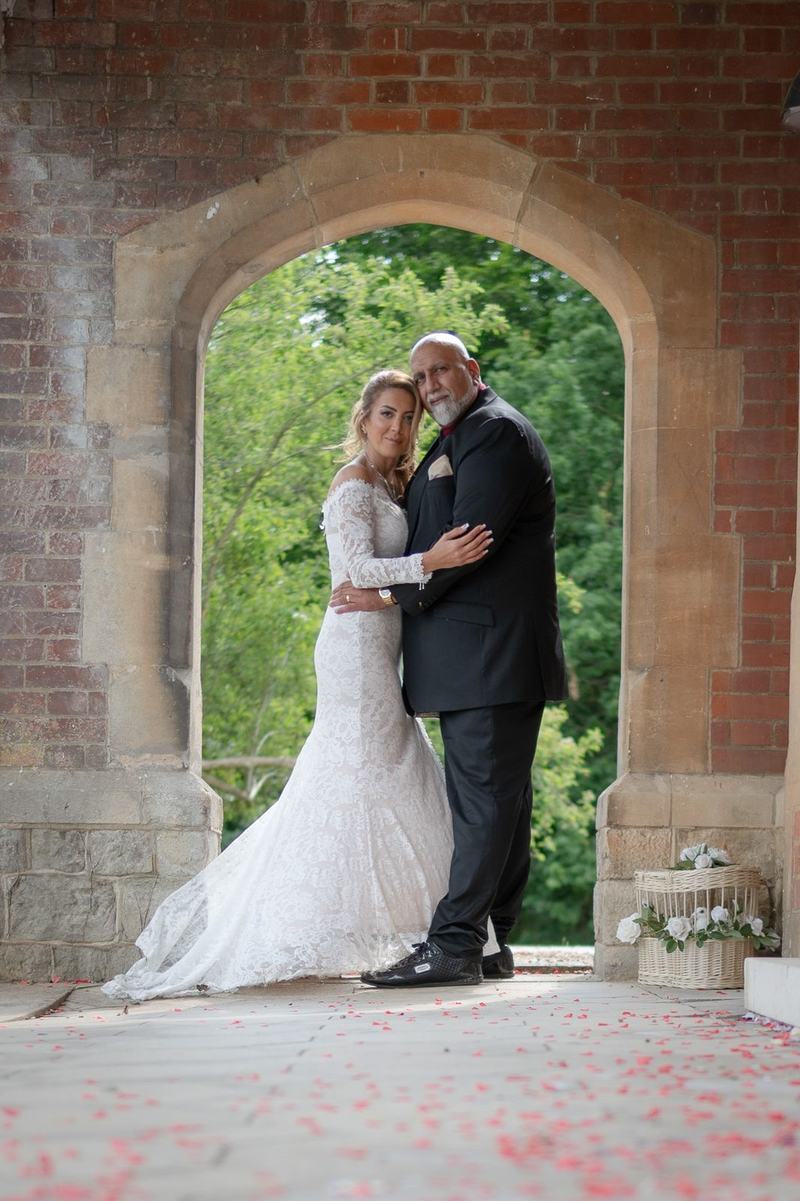 Bride and groom embracing under a stone archway