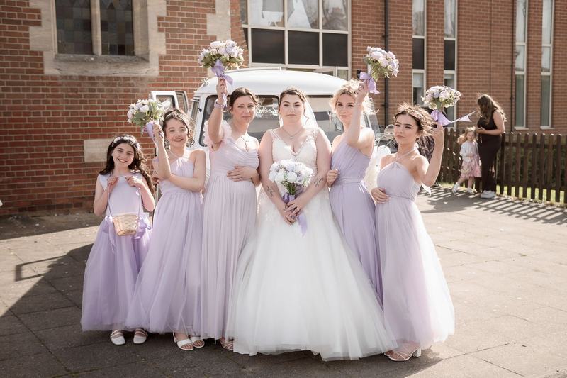 Bride with bridesmaids and flower girl outside a church