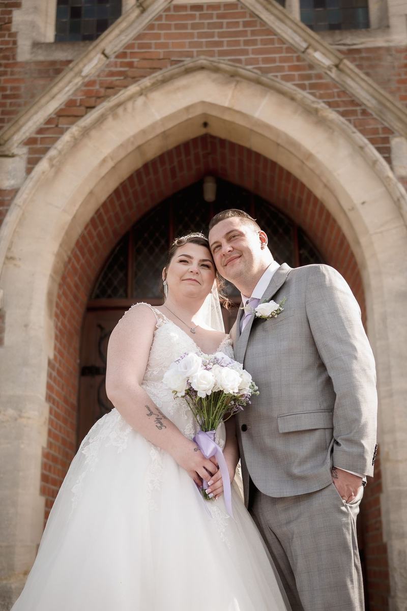 Bride and groom smiling under a church archway