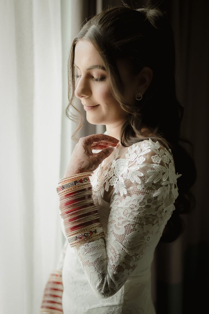 Bride in window light adjusting her sleeve
