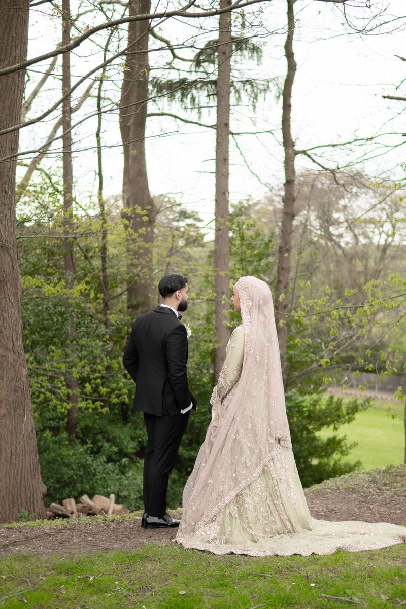 Bride and groom facing each other in a woodland setting