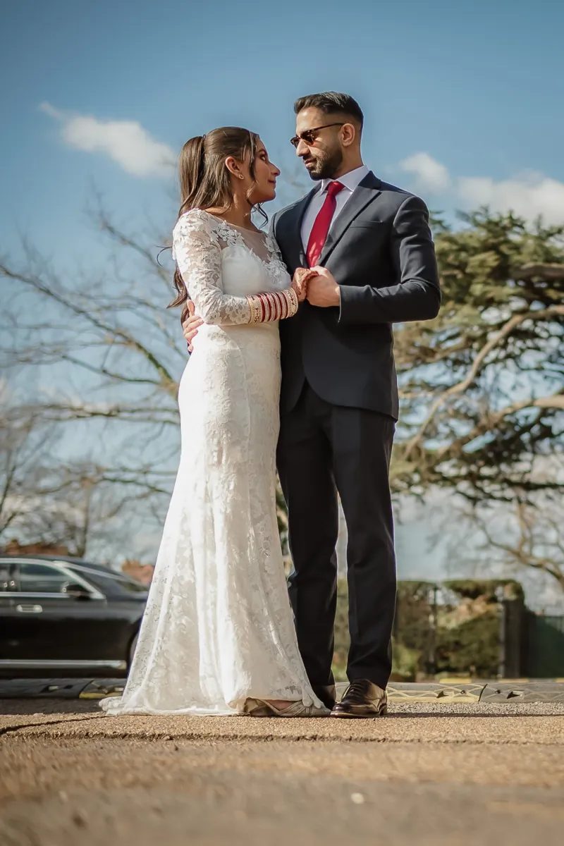 Bride and groom looking at each other under a blue sky
