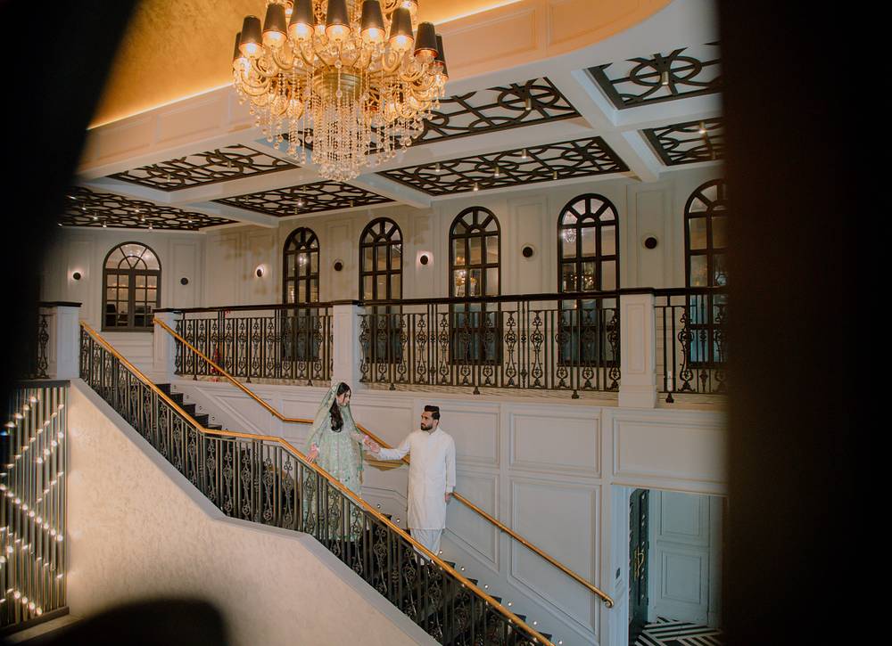 The couple on the grand staircase beneath the chandelier