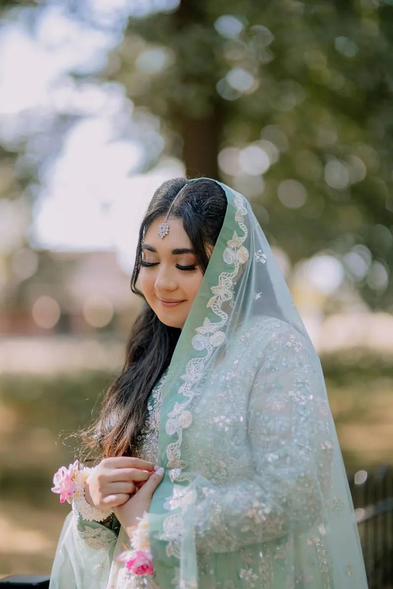 The bride, eyes closed, beneath the trees