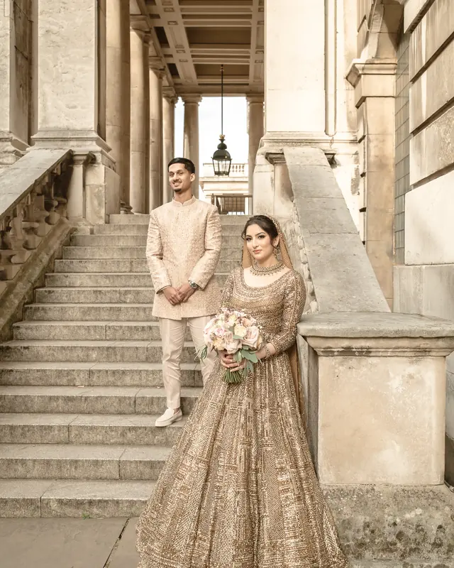 The couple on the colonnade steps with a bouquet of blush roses