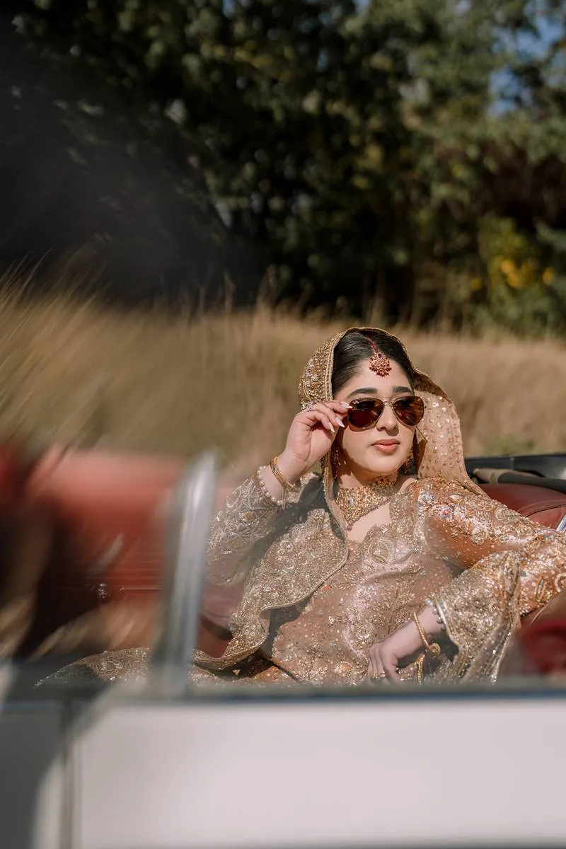 The bride lowers her sunglasses in the vintage car