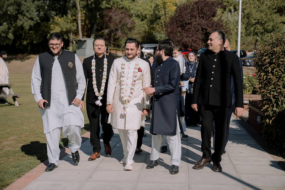 The groom arrives with his family, garlanded and smiling
