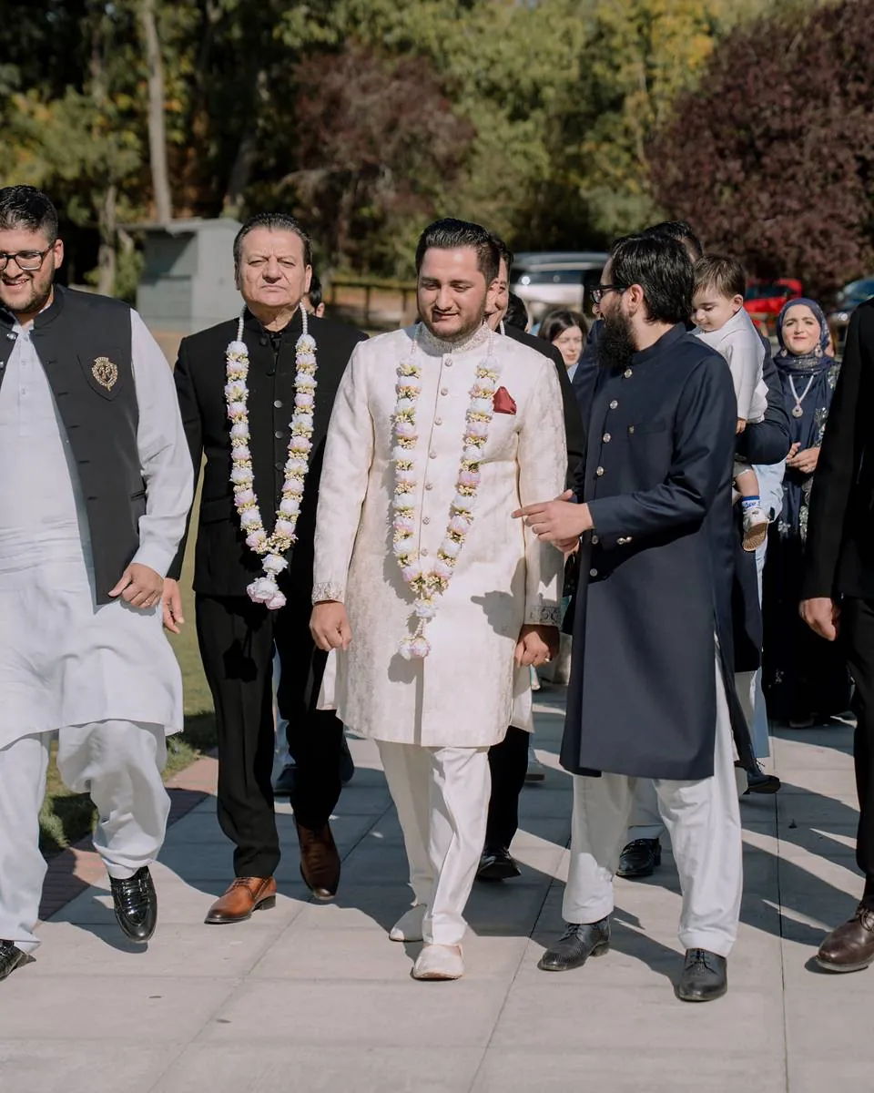 The groom, wearing a floral garland, walking in with his family