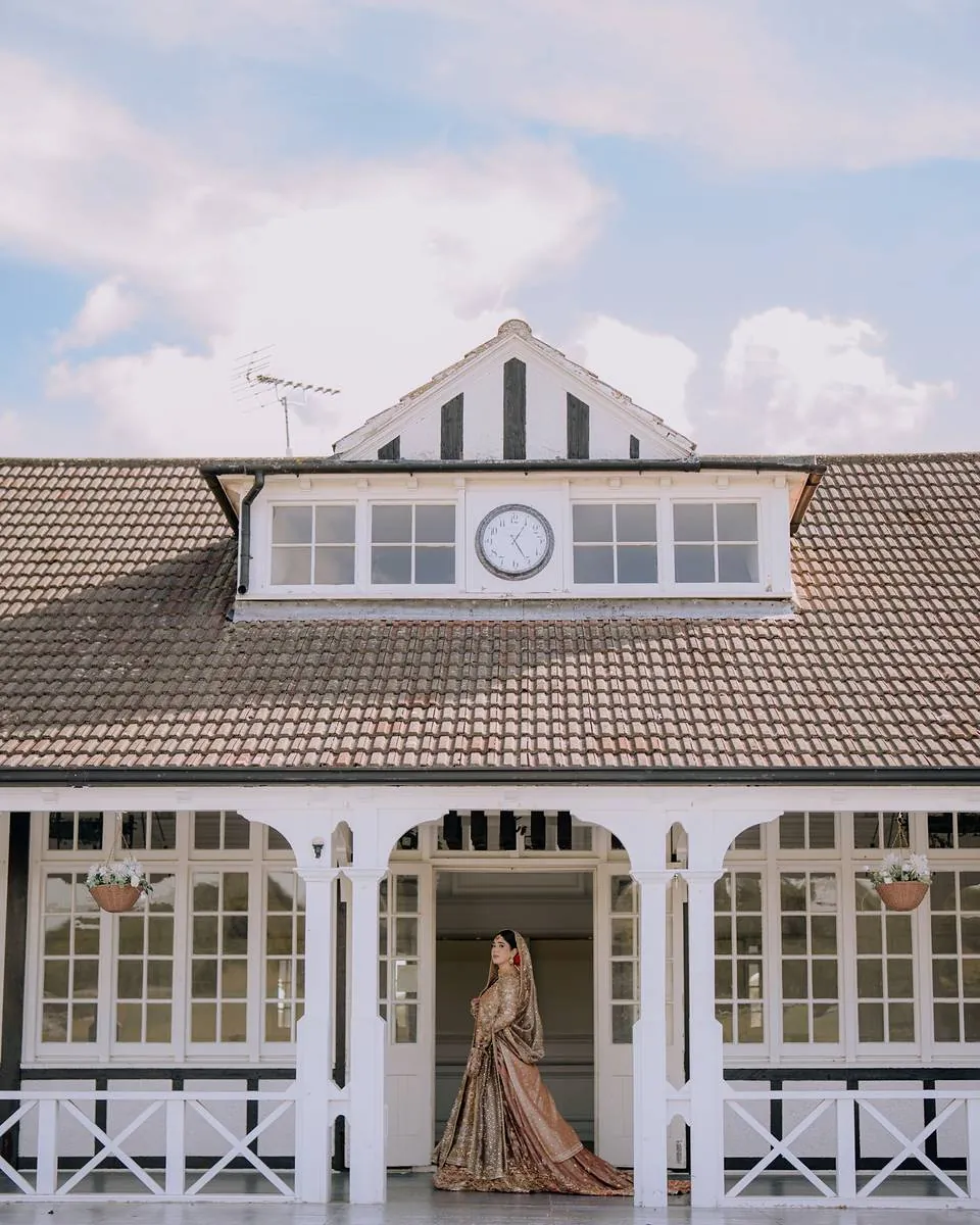 The bride standing on the veranda of the white Shenley clubhouse