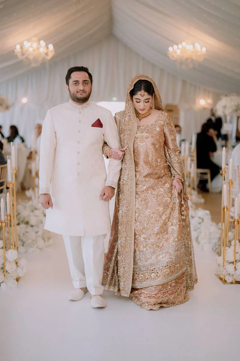 The couple walking down the marquee aisle