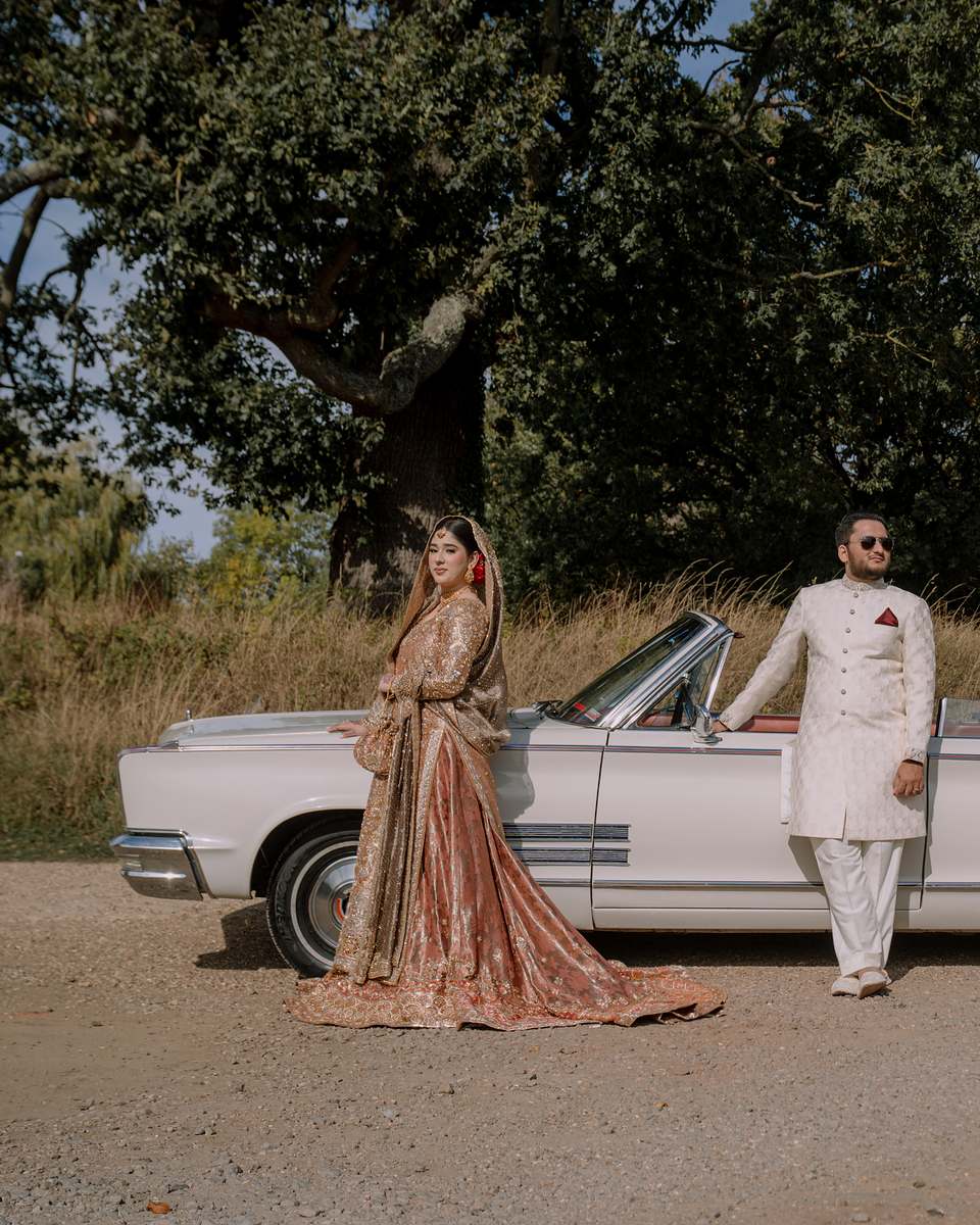 The bride and groom beside the white vintage Cadillac on the Shenley Club driveway