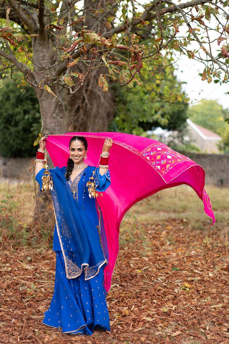 A pink phulkari dupatta caught in the wind