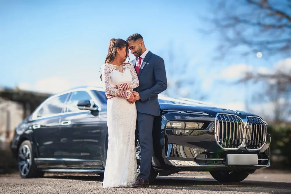 Foreheads touching beside the wedding car