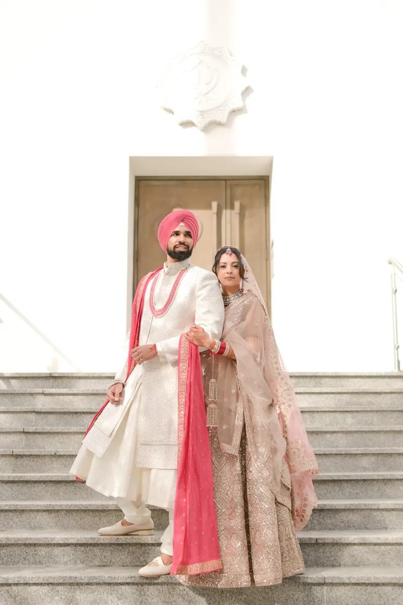 Bride and groom posing on the steps outside a Gurdwara