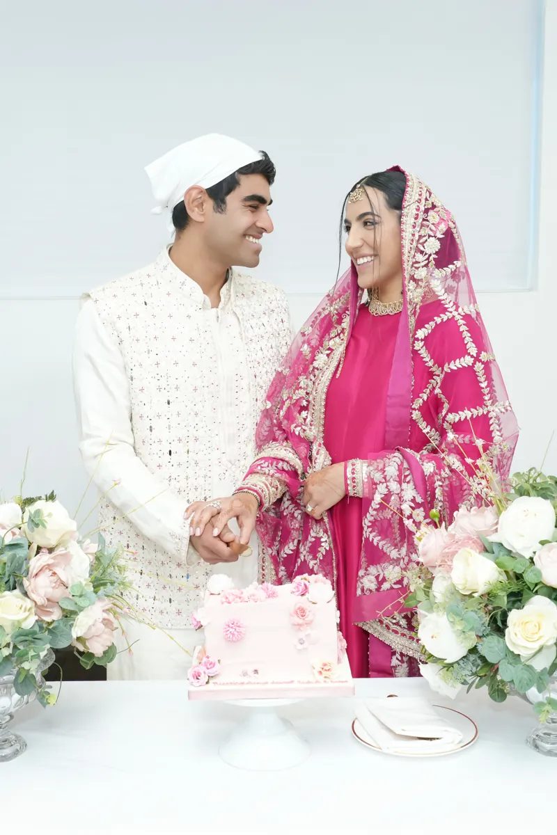 Bride and groom smiling at each other as they cut their cake